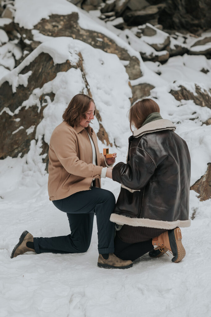 Same sex couple sharing a proposal moment in the snow in Stowe, Vermont during winter